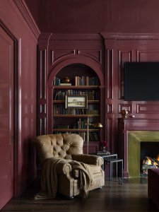 moody dramatic library space with burgundy, deep red walls, high gloss finish, and tufted accents chair. 